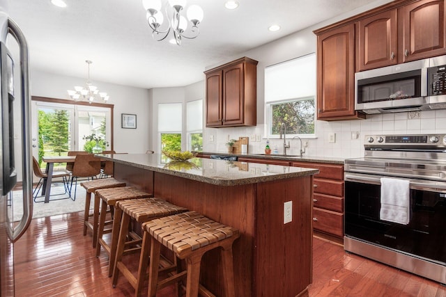 6923 Bishops Crossing Cir, Dublin, OH 43016 - kitchen featuring appliances with stainless steel finishes, a chandelier, dark wood finished floors, a kitchen island, and a breakfast bar area