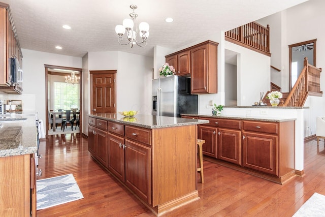 6923 Bishops Crossing Cir, Dublin, OH 43016 - kitchen with a chandelier, stainless steel appliances, wood finished floors, a kitchen island, and light stone counters
