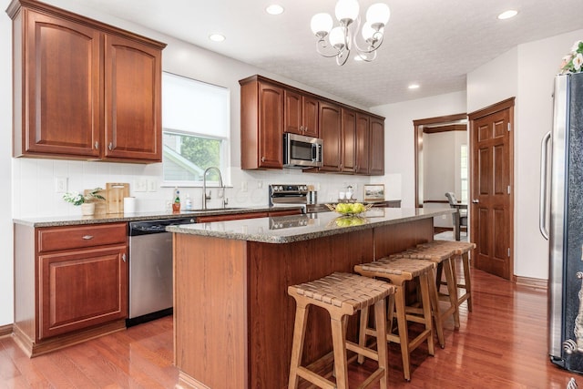 6923 Bishops Crossing Cir, Dublin, OH 43016 - kitchen with stainless steel appliances, a breakfast bar area, a chandelier, decorative backsplash, and recessed lighting