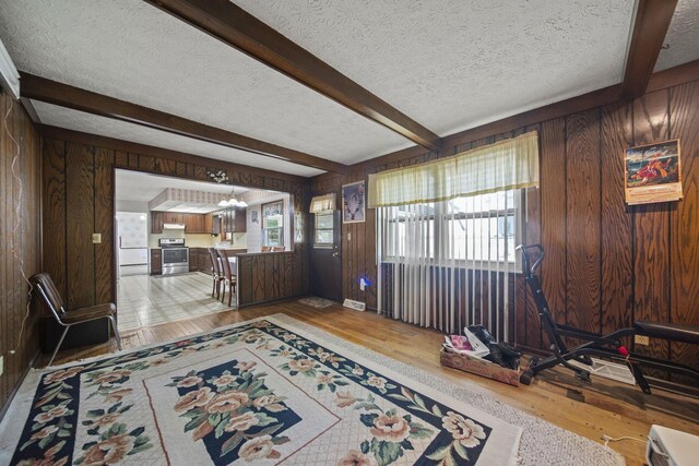 6329 Birkewood St, Columbus, OH 43229 - foyer entrance with wooden walls, a textured ceiling, light wood-style floors, and beamed ceiling