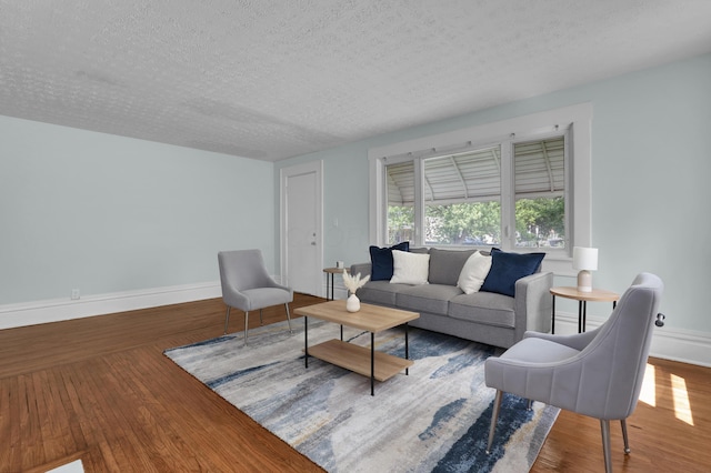 living room with a textured ceiling, baseboards, and wood finished floors