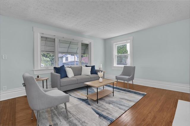 living area featuring a textured ceiling, wood finished floors, and baseboards
