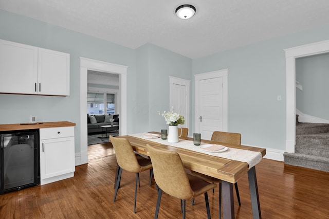 dining room with beverage cooler, dark wood-style flooring, stairway, and baseboards
