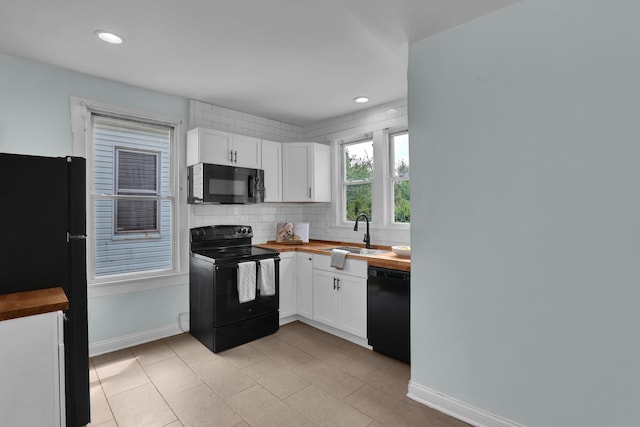 kitchen featuring black appliances, wooden counters, a sink, white cabinetry, and tasteful backsplash