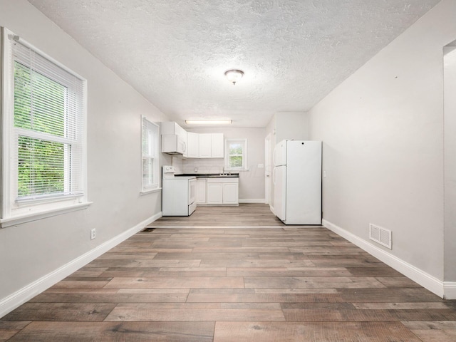 84 Meek Ave, Columbus, OH 43222 - kitchen featuring white appliances, light wood-style flooring, a textured ceiling, white cabinetry, and baseboards