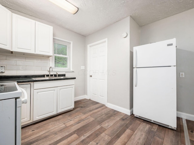 84 Meek Ave, Columbus, OH 43222 - kitchen featuring freestanding refrigerator, stove, light wood-type flooring, white cabinetry, and a textured ceiling