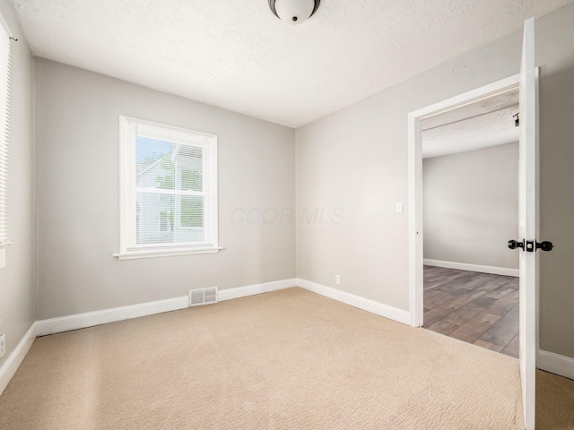 84 Meek Ave, Columbus, OH 43222 - unfurnished room with carpet floors, baseboards, a textured ceiling, and wood finished floors