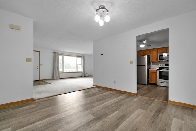 6301 Columbus Rd, Centerburg, OH 43011 - unfurnished living room with light wood-style flooring, baseboards, and a textured ceiling