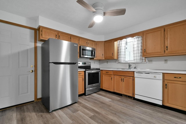 6301 Columbus Rd, Centerburg, OH 43011 - kitchen featuring stainless steel appliances, light countertops, a ceiling fan, light wood-style flooring, and a sink