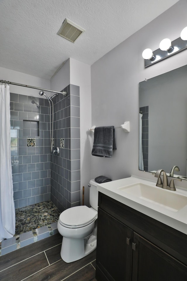 524 Autumn Ridge Cir, Pickerington, OH 43147 - bathroom featuring wood finished floors, toilet, a tile shower, vanity, and a textured ceiling