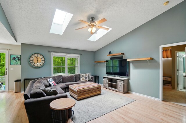 6963 Weurful Dr, Canal Winchester, OH 43110 - living area with a skylight, vaulted ceiling, light wood-style floors, ceiling fan, and a textured ceiling