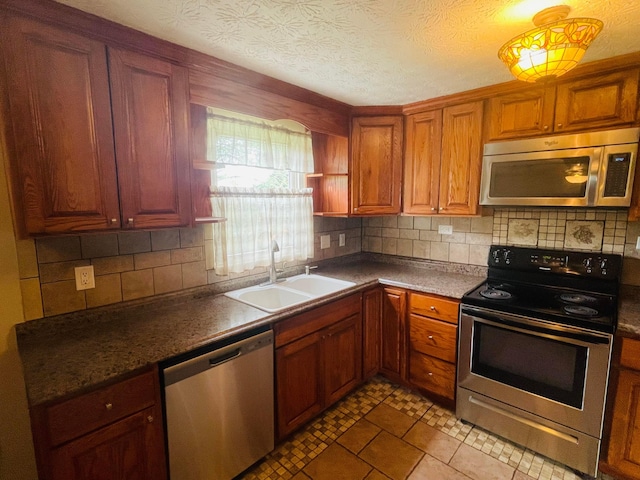 1275 Hathersage Pl, Galloway, OH 43119 - kitchen featuring stainless steel appliances, a sink, brown cabinetry, and backsplash