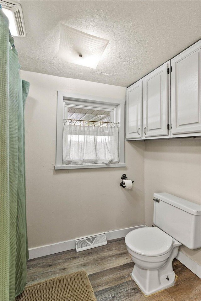 11526 Horseshoe Channel Dr, Lakeview, OH 43331 - bathroom with wood finished floors, toilet, baseboards, a textured ceiling, and a shower with shower curtain