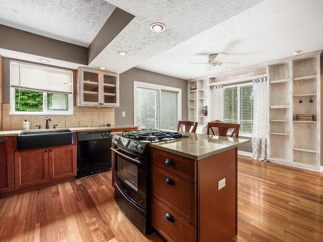 7020 Avery Rd, Dublin, OH 43017 - kitchen featuring black appliances, a sink, a textured ceiling, hardwood / wood-style floors, and light stone countertops