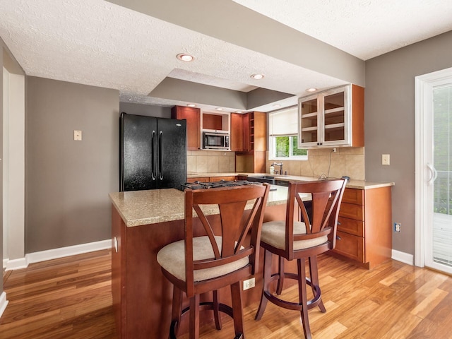 7020 Avery Rd, Dublin, OH 43017 - kitchen featuring freestanding refrigerator, stainless steel microwave, a textured ceiling, baseboards, and tasteful backsplash