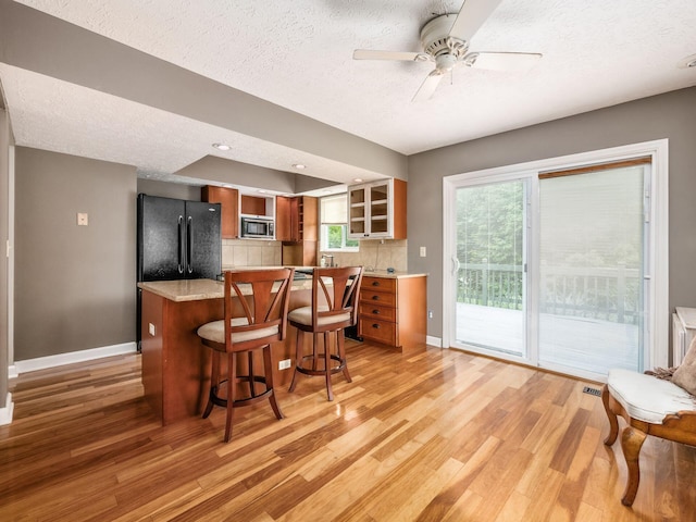 7020 Avery Rd, Dublin, OH 43017 - kitchen featuring freestanding refrigerator, light wood finished floors, a textured ceiling, stainless steel microwave, and baseboards