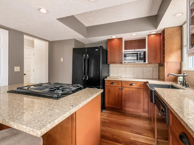 7020 Avery Rd, Dublin, OH 43017 - kitchen featuring black appliances, a textured ceiling, light wood-style flooring, brown cabinets, and tasteful backsplash