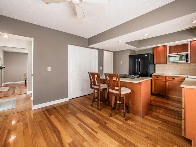 7020 Avery Rd, Dublin, OH 43017 - kitchen with freestanding refrigerator, wood finished floors, stainless steel microwave, a kitchen island, and baseboards
