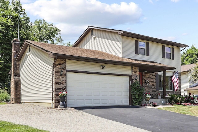 traditional home with a garage, driveway, brick siding, and a chimney