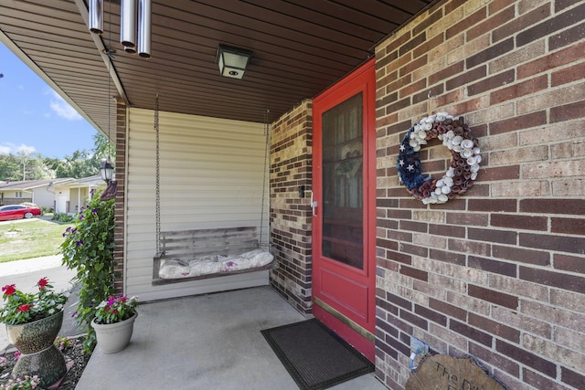 property entrance with covered porch and brick siding