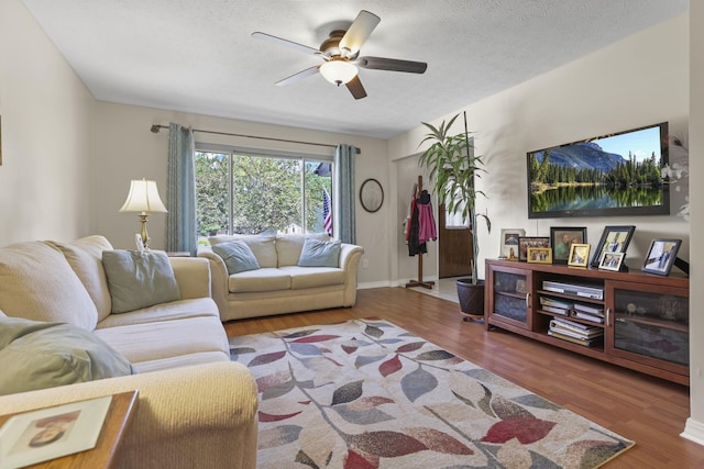 living room with wood finished floors, a ceiling fan, and a textured ceiling