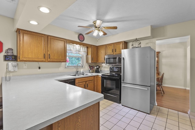 kitchen with stainless steel appliances, a sink, a ceiling fan, light countertops, and brown cabinets