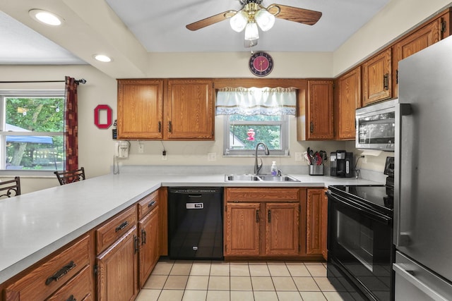 kitchen with black appliances, a sink, brown cabinetry, a ceiling fan, and light tile patterned floors