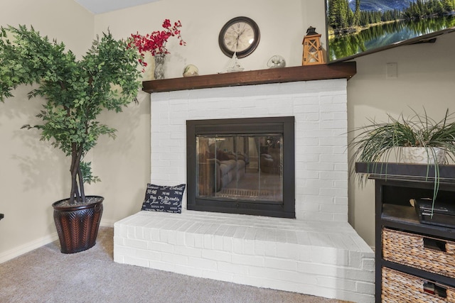 detailed view of carpet flooring, a brick fireplace, and baseboards