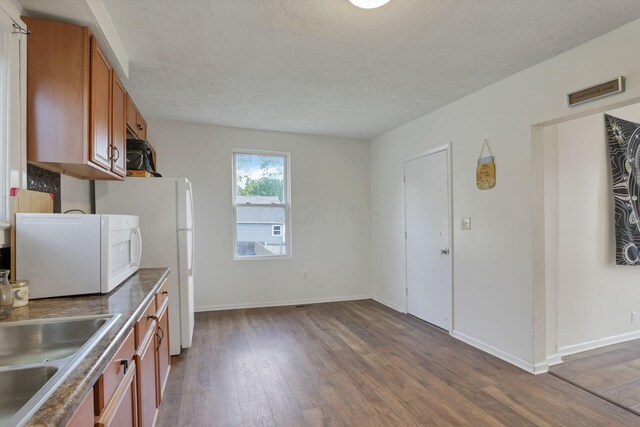 610 W Wheeling St, Lancaster, OH 43130 - kitchen featuring white appliances, brown cabinets, dark wood finished floors, a sink, and a textured ceiling