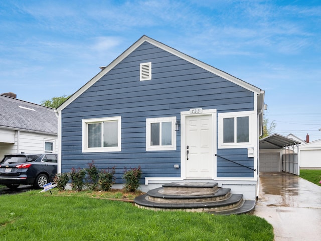 view of front of home with a front yard, an outdoor structure, driveway, a detached garage, and entry steps