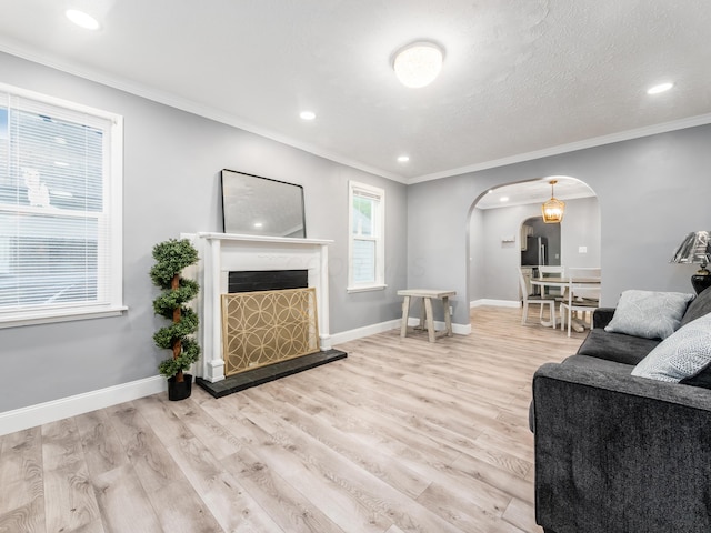 living area featuring arched walkways, wood finished floors, crown molding, recessed lighting, and baseboards
