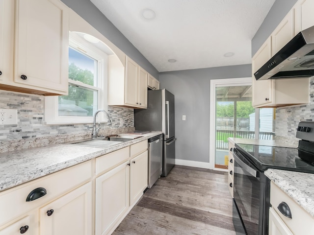 kitchen featuring electric range, under cabinet range hood, a sink, dishwasher, and baseboards