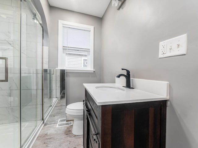bathroom with a stall shower, vanity, toilet, and wood finished floors