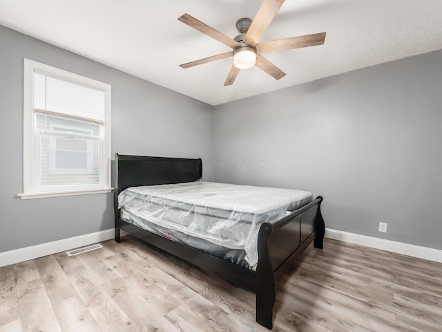 bedroom featuring baseboards, wood finished floors, and ceiling fan