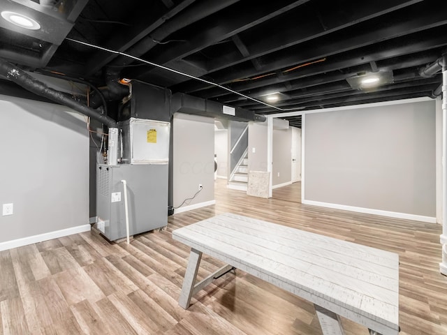 finished below grade area with heating unit, wood finished floors, stairway, and baseboards