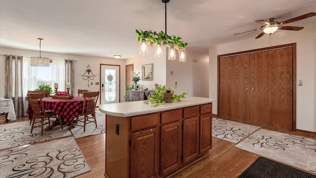 3890 Township Road 70 NW, Somerset, OH 43783 - kitchen with light wood finished floors, ceiling fan, light countertops, hanging light fixtures, and brown cabinetry