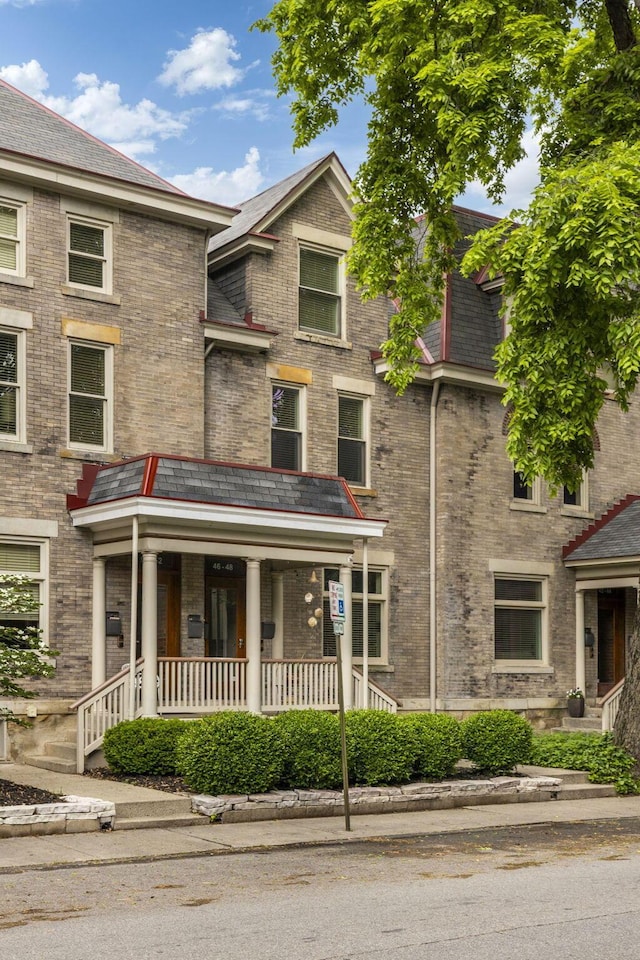 multi unit property featuring covered porch and brick siding