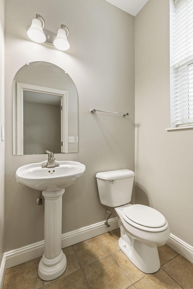 bathroom with baseboards, toilet, and tile patterned flooring