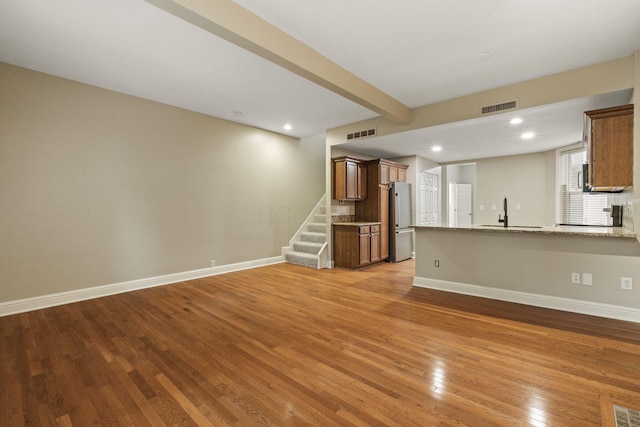unfurnished living room featuring light wood-style floors, baseboards, a sink, stairway, and recessed lighting