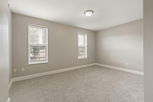 carpeted spare room featuring baseboards