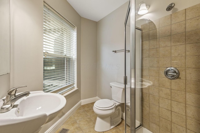 full bath featuring a sink, a shower stall, tile patterned flooring, toilet, and plenty of natural light