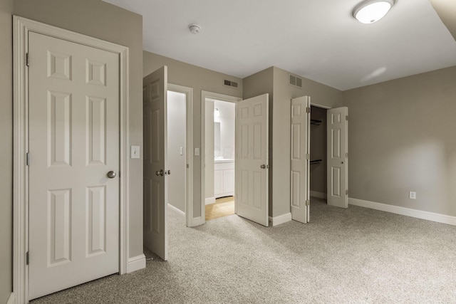 unfurnished bedroom with carpet, baseboards, a closet, and connected bathroom