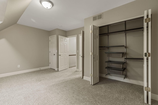 unfurnished bedroom with carpet flooring, baseboards, a closet, and vaulted ceiling