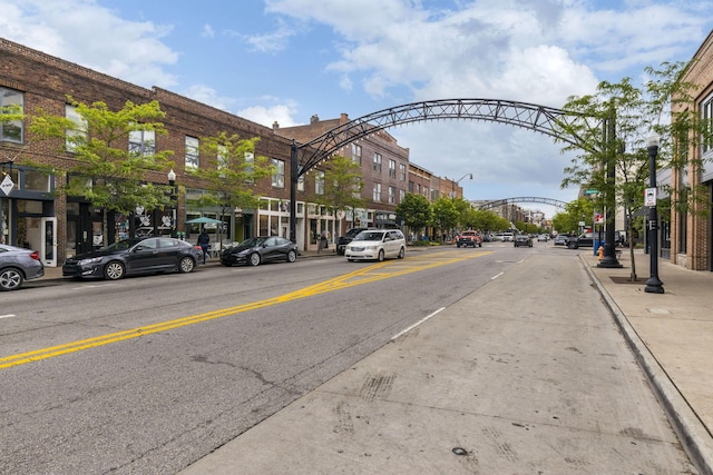 view of asphalt street featuring street lights, sidewalks, and curbs