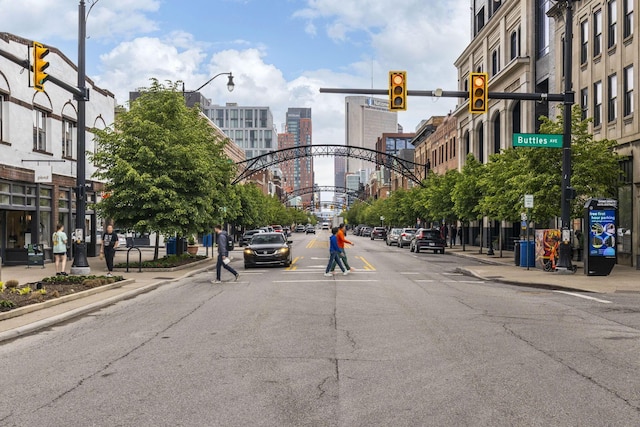 view of asphalt road with sidewalks, street lighting, traffic lights, and curbs