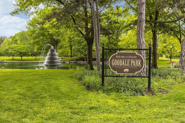 community / neighborhood sign with a water view and a lawn