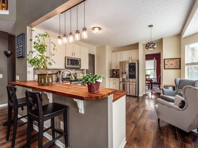 299 Stonhope Dr, Delaware, OH 43015 - kitchen featuring wooden counters, appliances with stainless steel finishes, a peninsula, tasteful backsplash, and dark wood-style flooring
