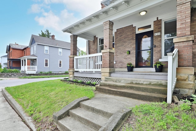 459 E Whittier St, Columbus, OH 43206 - view of exterior entry featuring a porch, brick siding, and a lawn