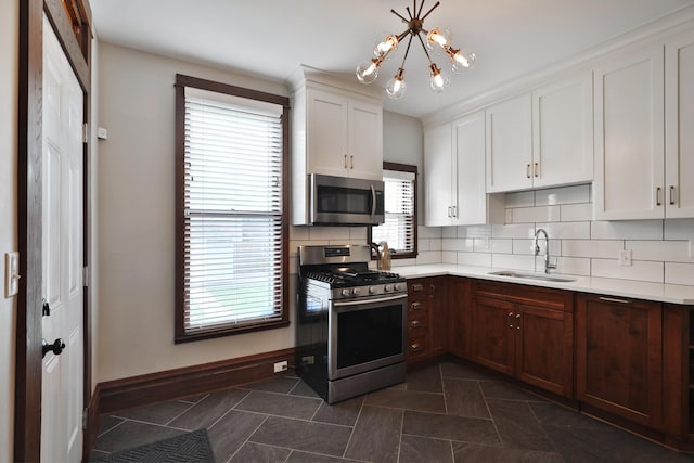 459 E Whittier St, Columbus, OH 43206 - kitchen with appliances with stainless steel finishes, a sink, light countertops, a chandelier, and backsplash
