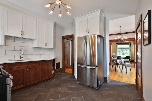 459 E Whittier St, Columbus, OH 43206 - kitchen with stainless steel appliances, a chandelier, a sink, and white cabinetry